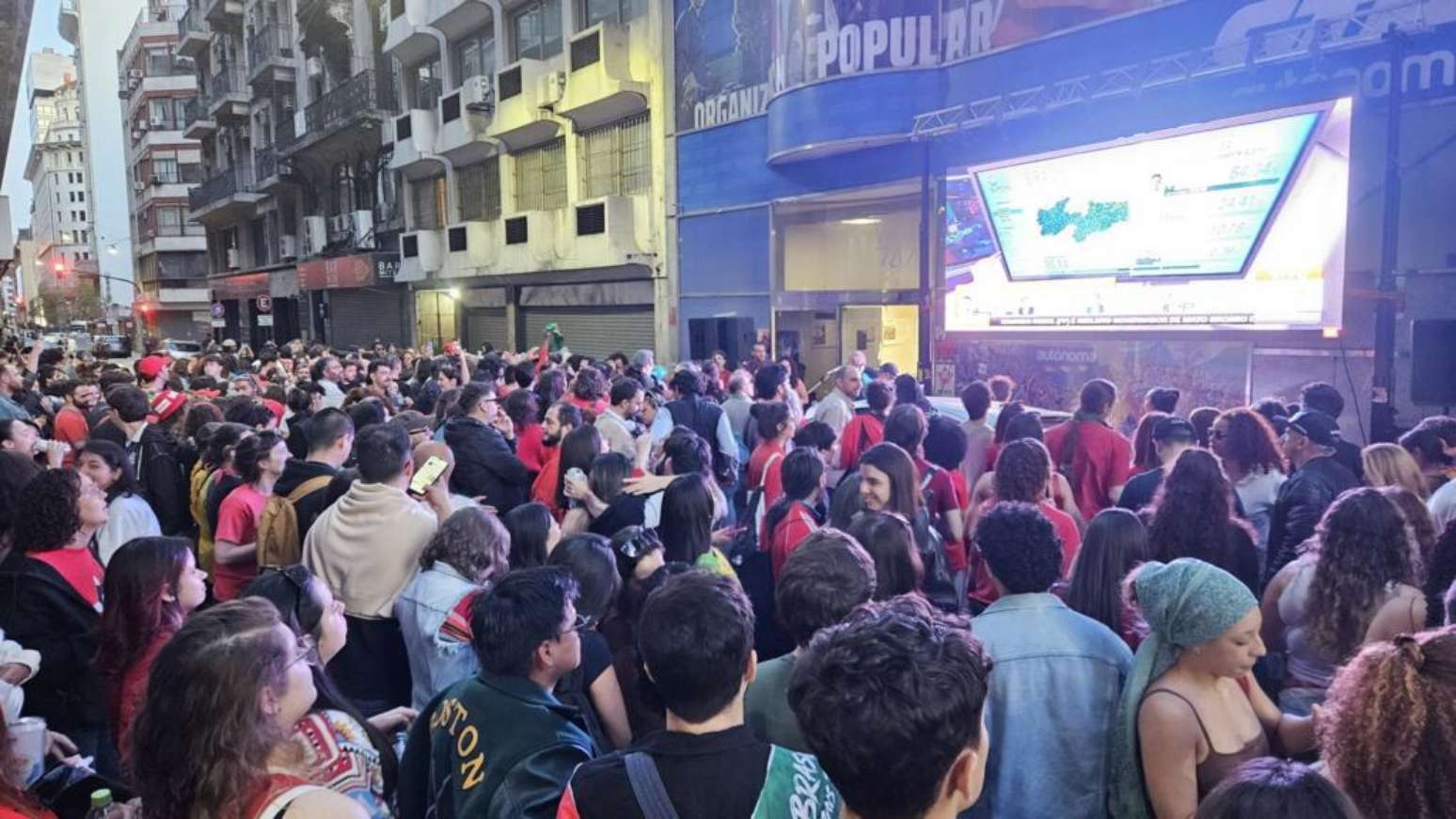 Em Buenos Aires, eleitores do presidente Lula acompanham a apuração dos votos diante de um telão.